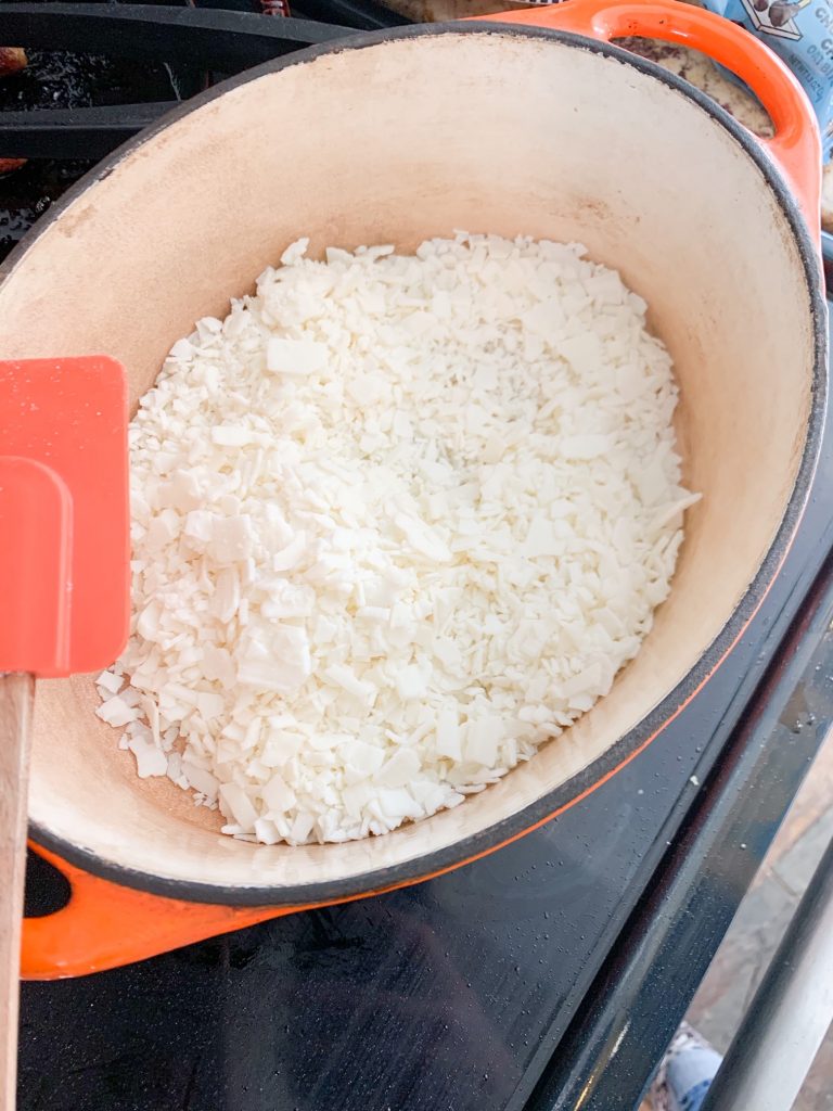 soy wax in a large oval bright orange dutch oven for making fire starters.