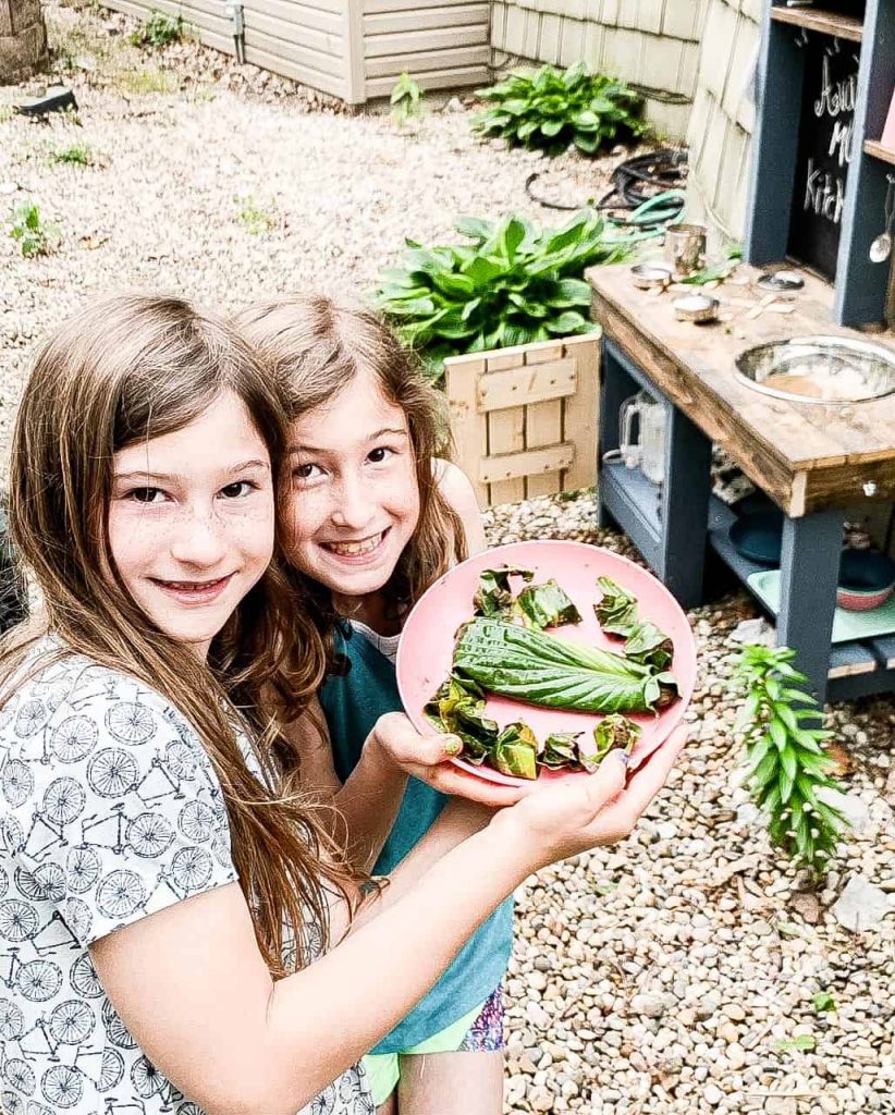 2 girls making spinach wraps and Brussel sprouts for preteen in a children's wooden mud kitchen
