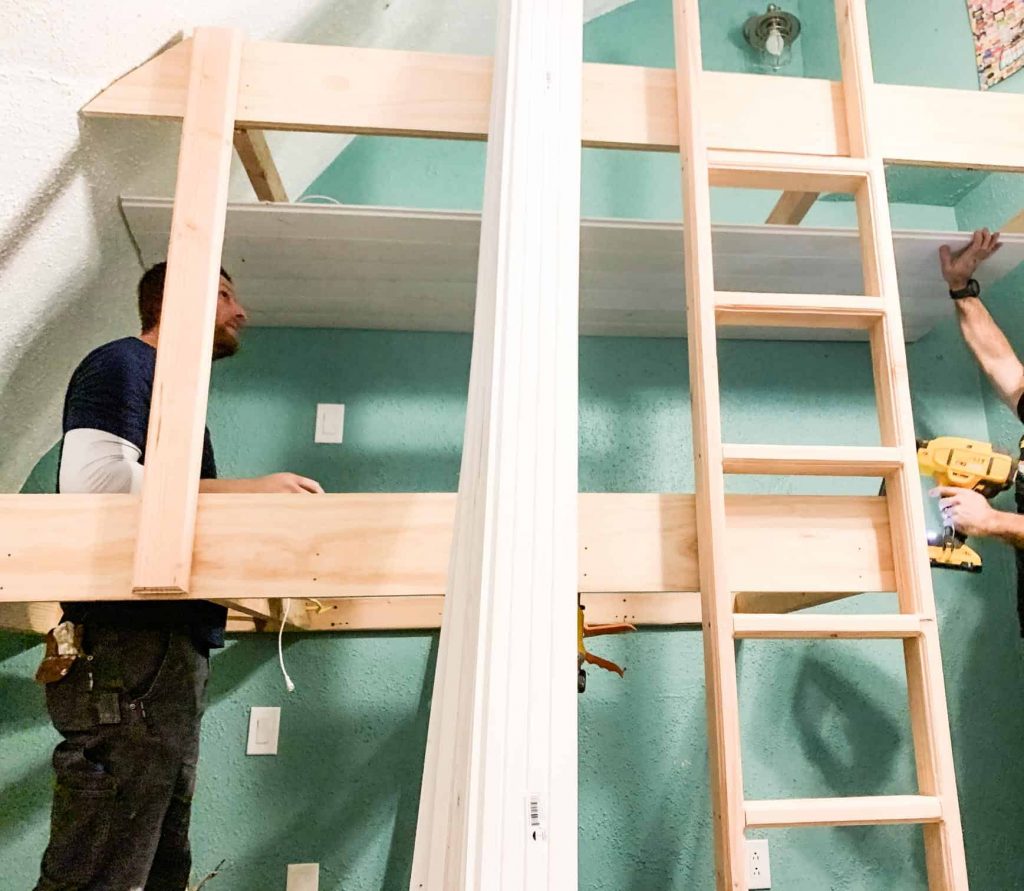 triple bed wooden framing and paneling being put in by two guys