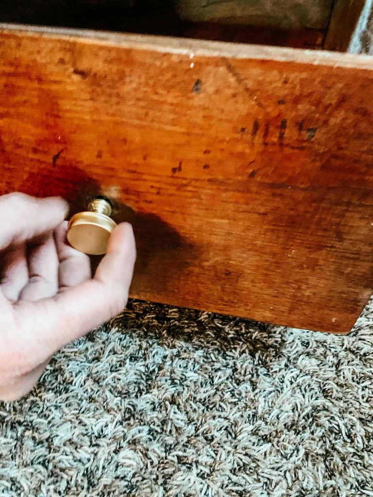 wooden drawer with hand putting in a gold knob